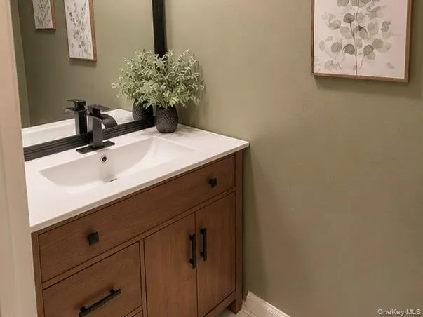 Modern vanity featuring a white integrated sink, matte black faucet, and wood-finish cabinetry with dark hardware Modern vanity featuring a white integrated sink, matte black faucet, and wood-finish cabinetry with dark hardware