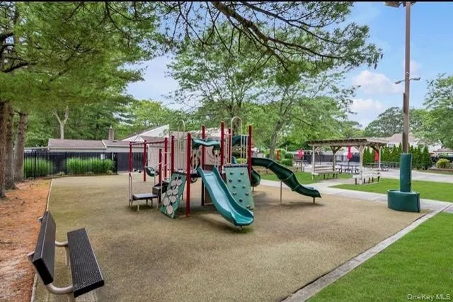 Outdoor recreational area featuring a multi-level play structure, two slides, climbing features, and a soft-surface ground cover Outdoor recreational area featuring a multi-level play structure, two slides, climbing features, and a soft-surface ground cover
