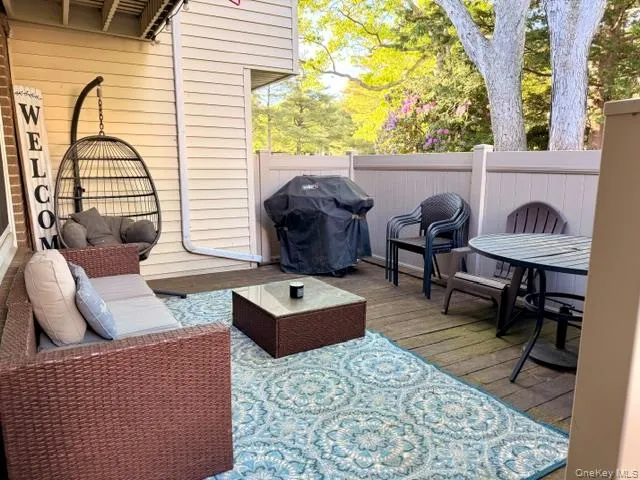 Outdoor patio featuring wood-finish decking, vinyl siding, and a privacy fence Outdoor patio featuring wood-finish decking, vinyl siding, and a privacy fence