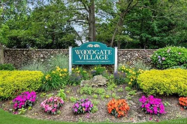 Woodgate Village entrance sign featuring a stone wall backdrop Woodgate Village entrance sign featuring a stone wall backdrop