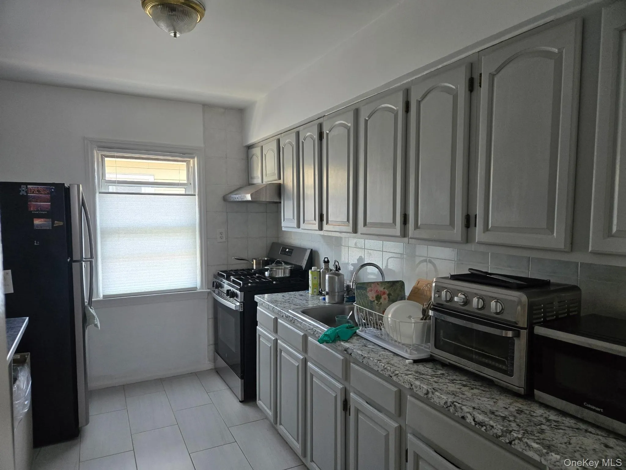 Kitchen featuring light-toned cabinetry, a stainless steel range with overhead hood, and a dual-basin sink Kitchen featuring light-toned cabinetry, a stainless steel range with overhead hood, and a dual-basin sink