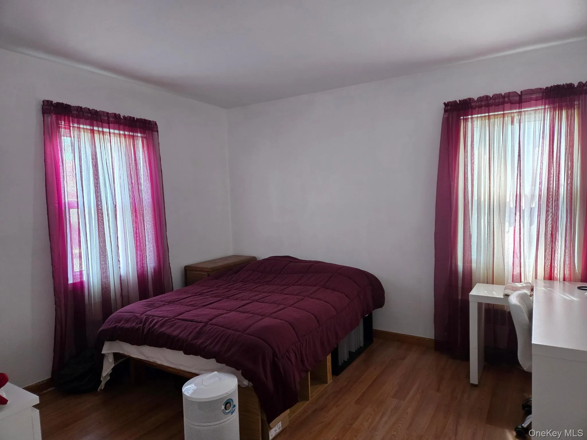 Bright room with wood-finish flooring and two windows Bright room with wood-finish flooring and two windows