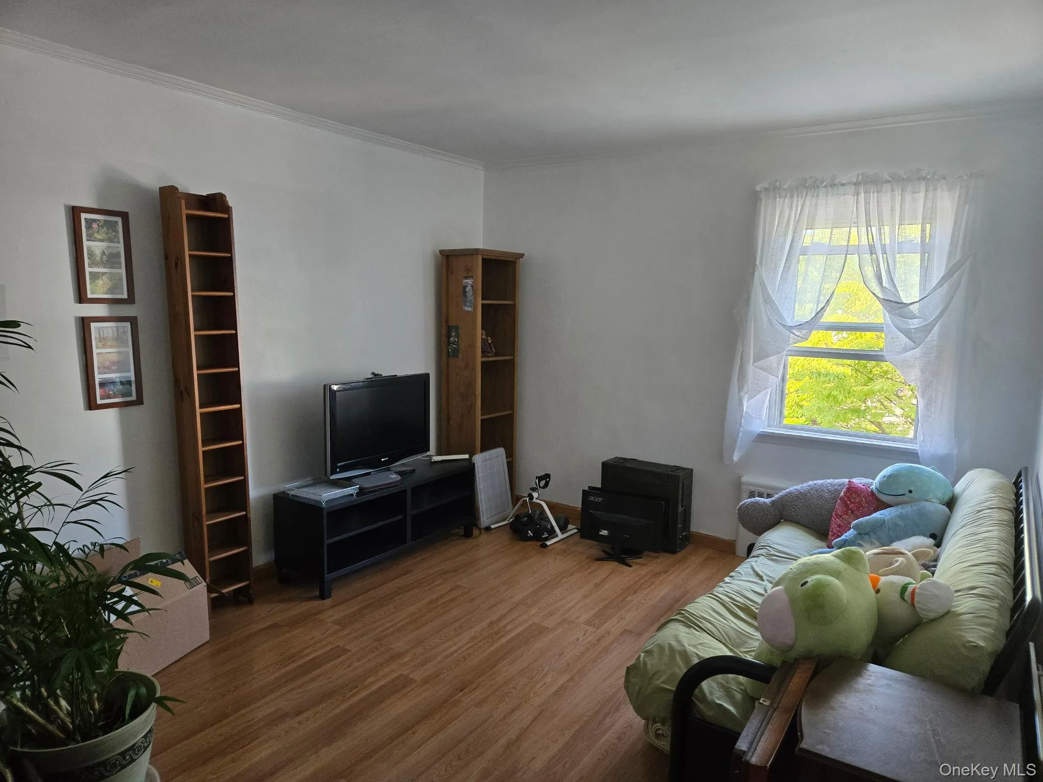 Room featuring wood-finish flooring, white walls, and crown molding Room featuring wood-finish flooring, white walls, and crown molding