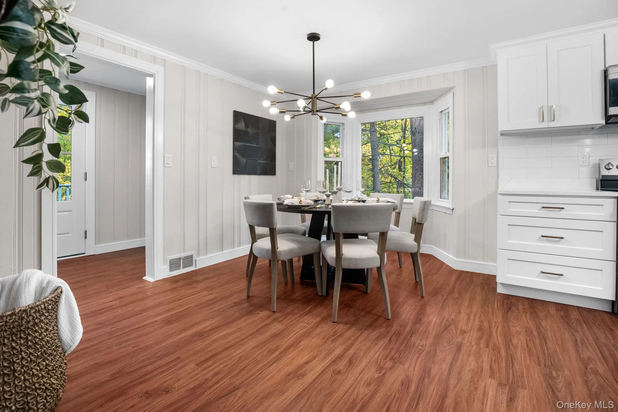 Charming dining nook with a modern chandelier and scenic window views, creating a warm setting for everyday meals or entertaining. Charming dining nook with a modern chandelier and scenic window views, creating a warm setting for everyday meals or entertaining.