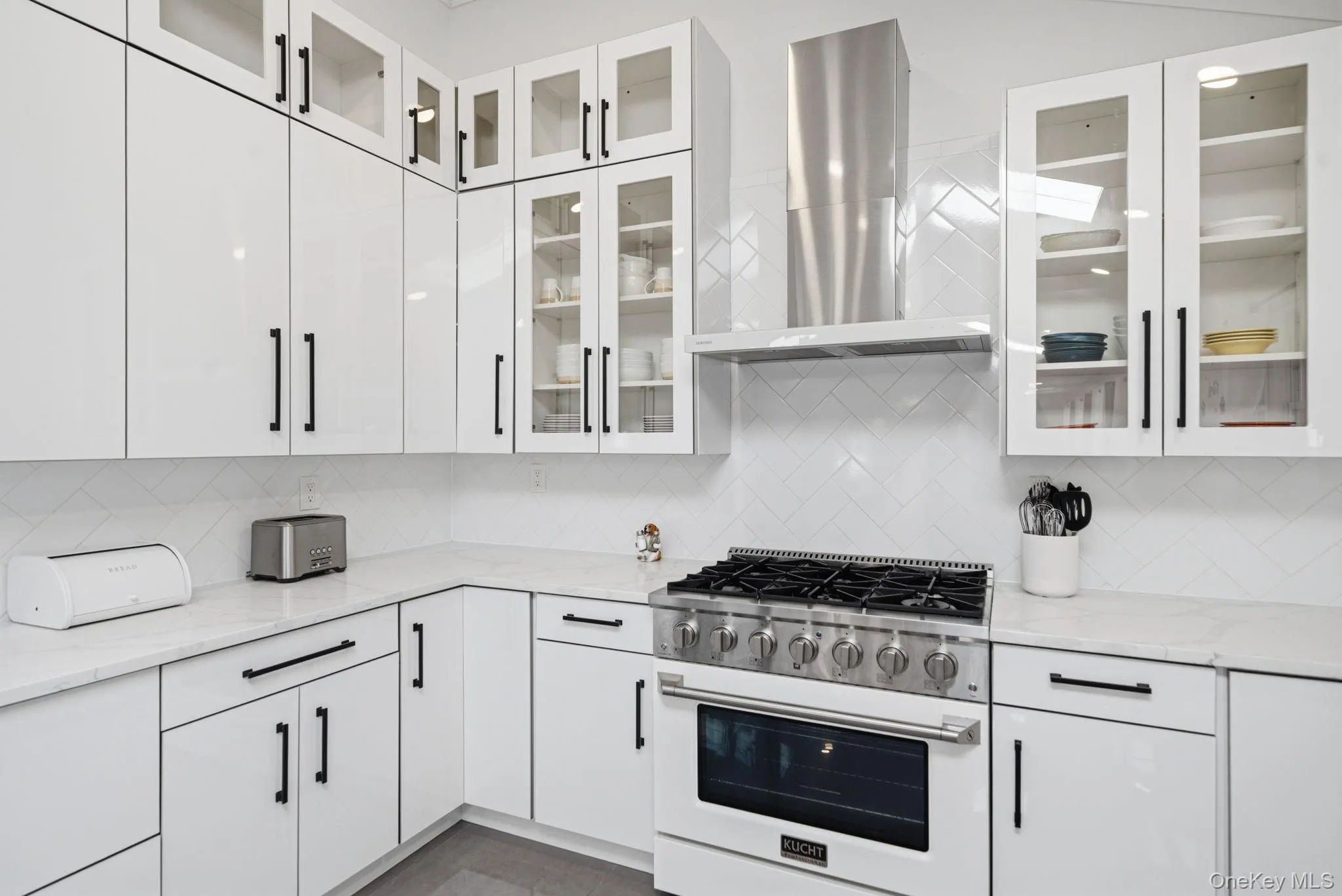 Bright and open renovated kitchen. Endless white cabinets and counter space. High end white appliances including natural gas cooking. Farm sink, skylight, recessed lighting, and porcelain tile flooring. Bright and open renovated kitchen. Endless white cabinets and counter space. High end white appliances including natural gas cooking. Farm sink, skylight, recessed lighting, and porcelain tile flooring.