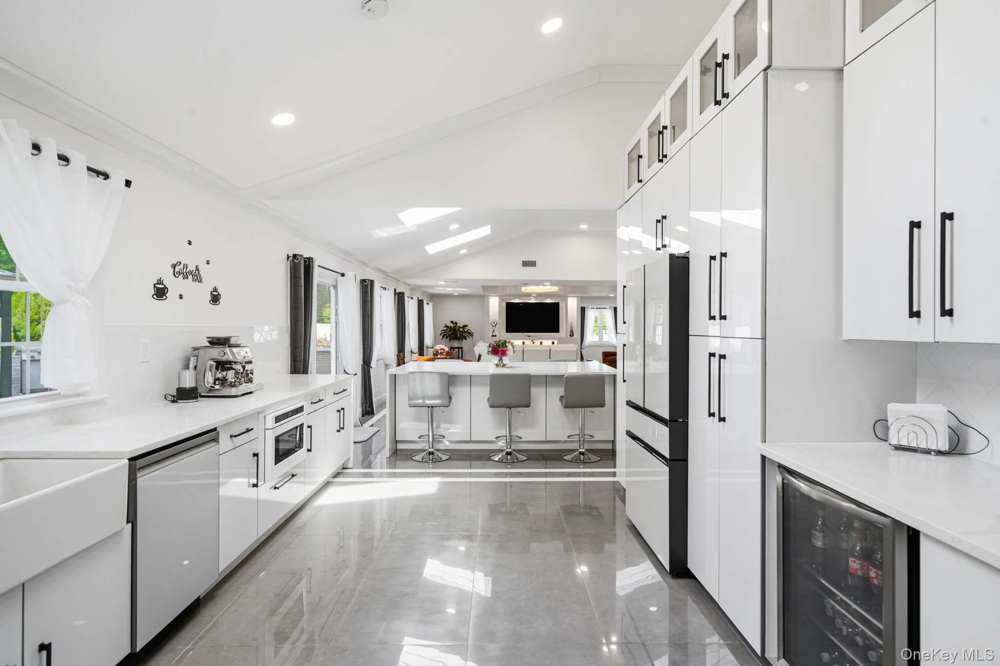Bright and open renovated kitchen. Endless white cabinets and counter space. High end white appliances including natural gas cooking. Farm sink, skylight, recessed lighting, and porcelain tile flooring. Bright and open renovated kitchen. Endless white cabinets and counter space. High end white appliances including natural gas cooking. Farm sink, skylight, recessed lighting, and porcelain tile flooring.