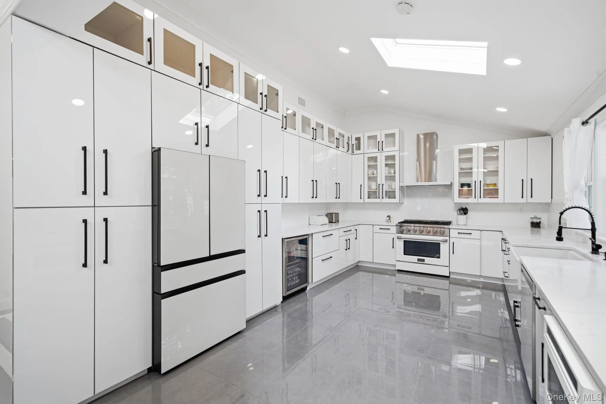 Bright and open renovated kitchen. Endless white cabinets and counter space. High end white appliances including natural gas cooking. Farm sink, skylight, recessed lighting, and porcelain tile flooring. Bright and open renovated kitchen. Endless white cabinets and counter space. High end white appliances including natural gas cooking. Farm sink, skylight, recessed lighting, and porcelain tile flooring.