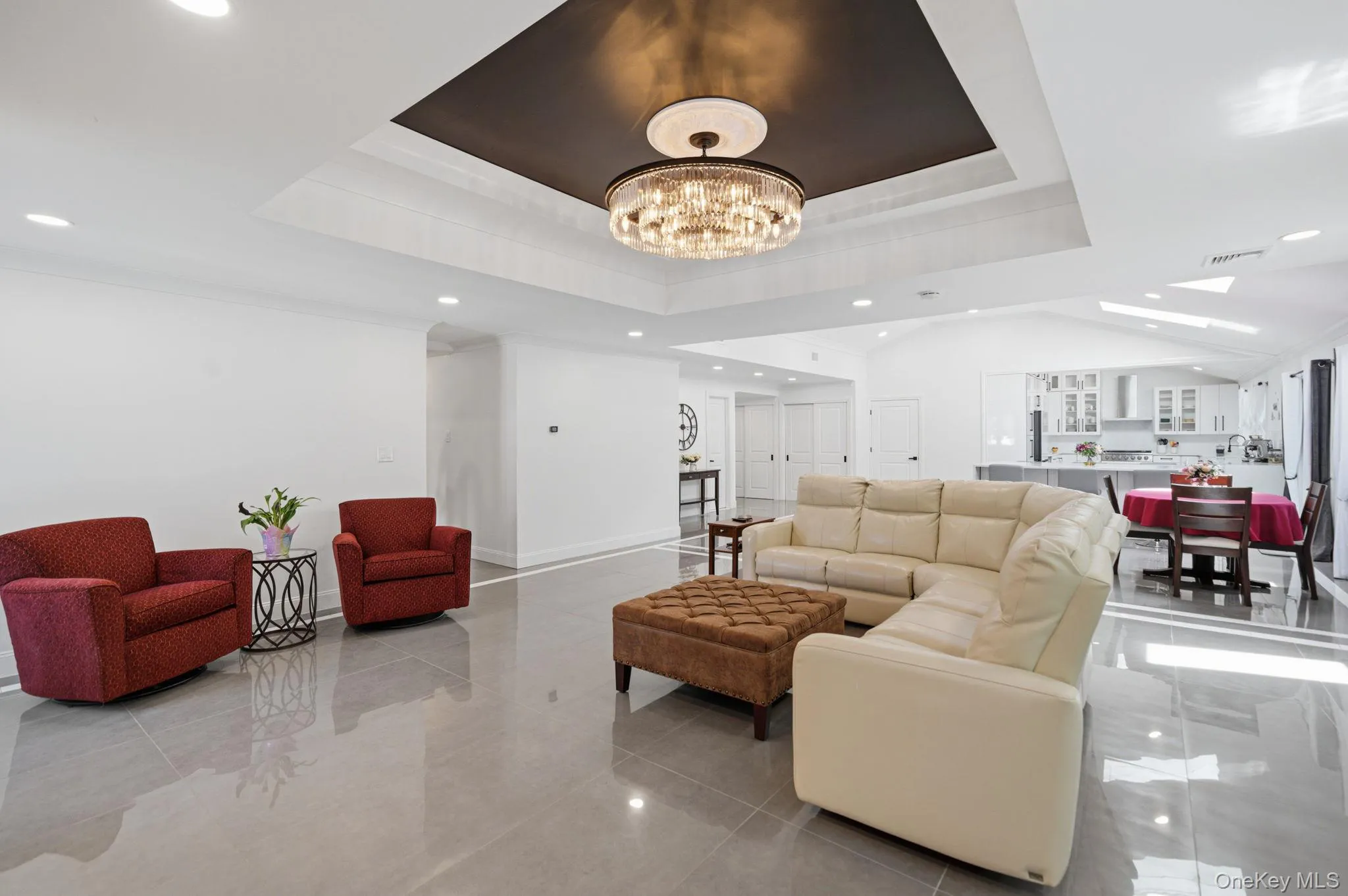 Open and bright living room with decorative ceiling, stunning chandelier, recessed lighting, wall of windows, electric fireplace and porcelain tile floors. Open and bright living room with decorative ceiling, stunning chandelier, recessed lighting, wall of windows, electric fireplace and porcelain tile floors.