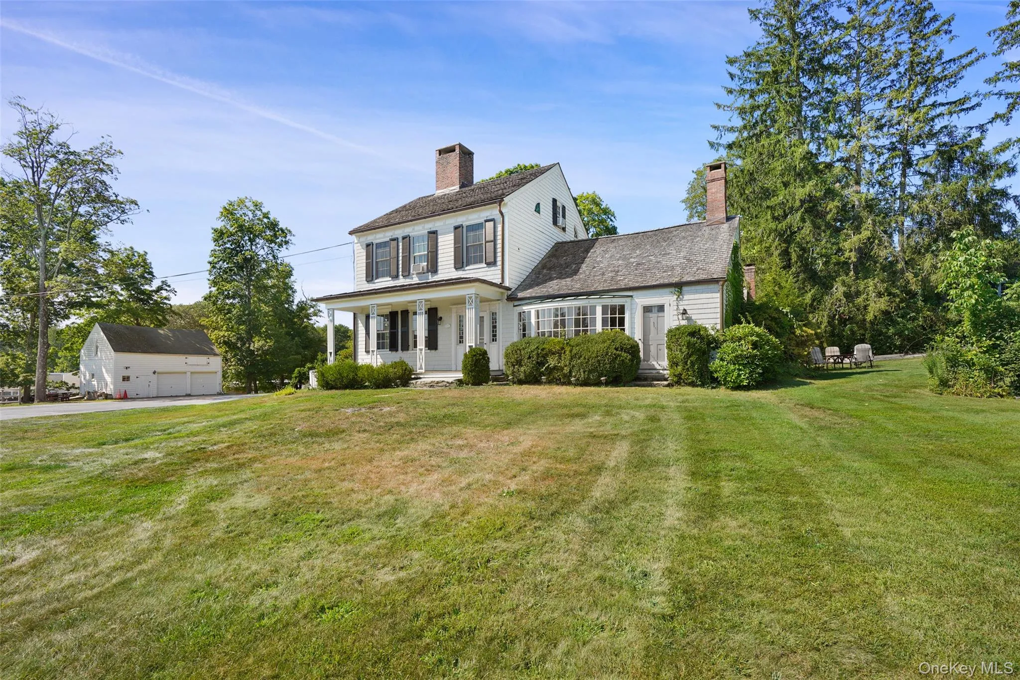 Colonial home with a porch, a chimney, a front lawn, and a detached garage 1 bay for renter Colonial home with a porch, a chimney, a front lawn, and a detached garage 1 bay for renter