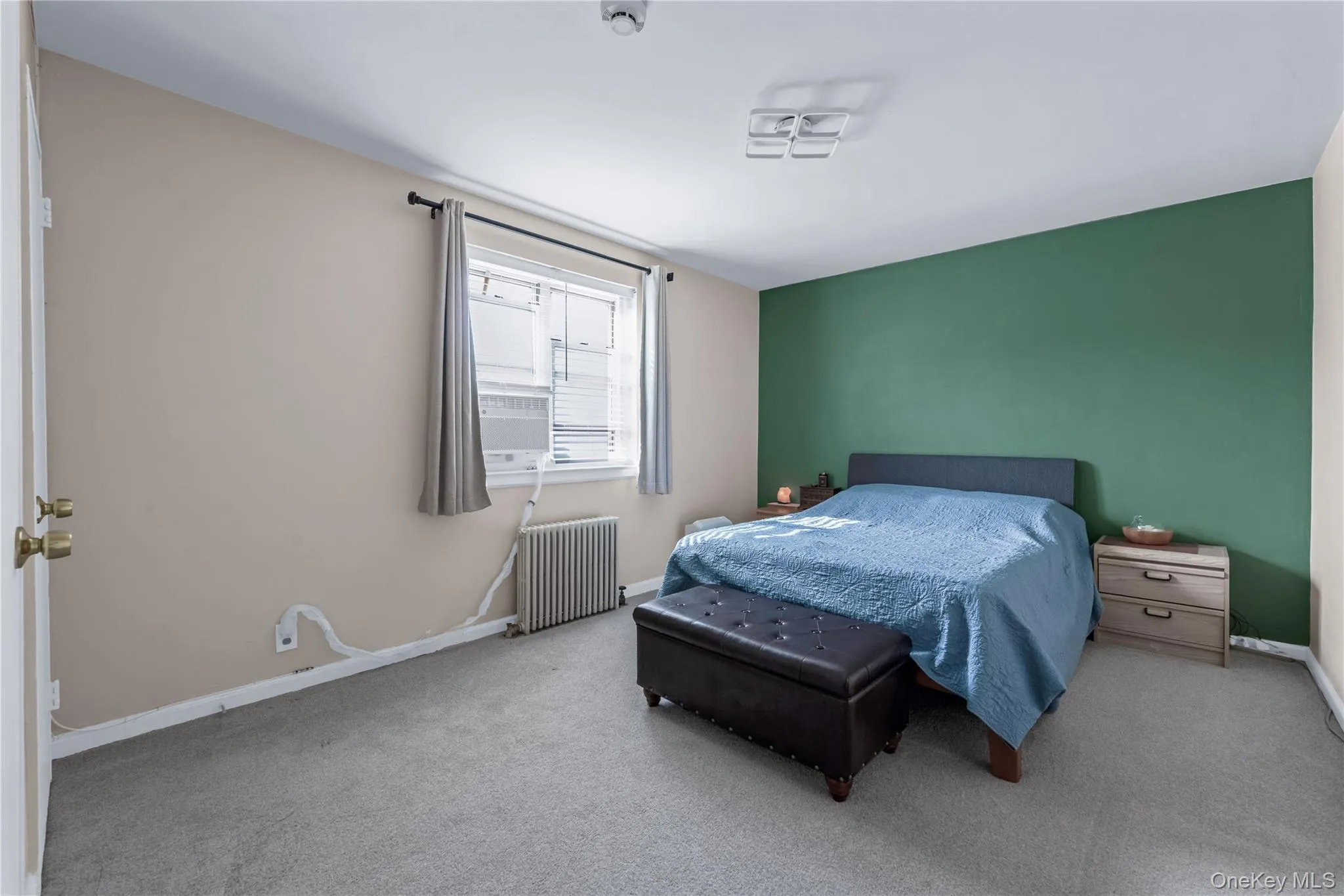 Carpeted bedroom featuring radiator and baseboards Carpeted bedroom featuring radiator and baseboards