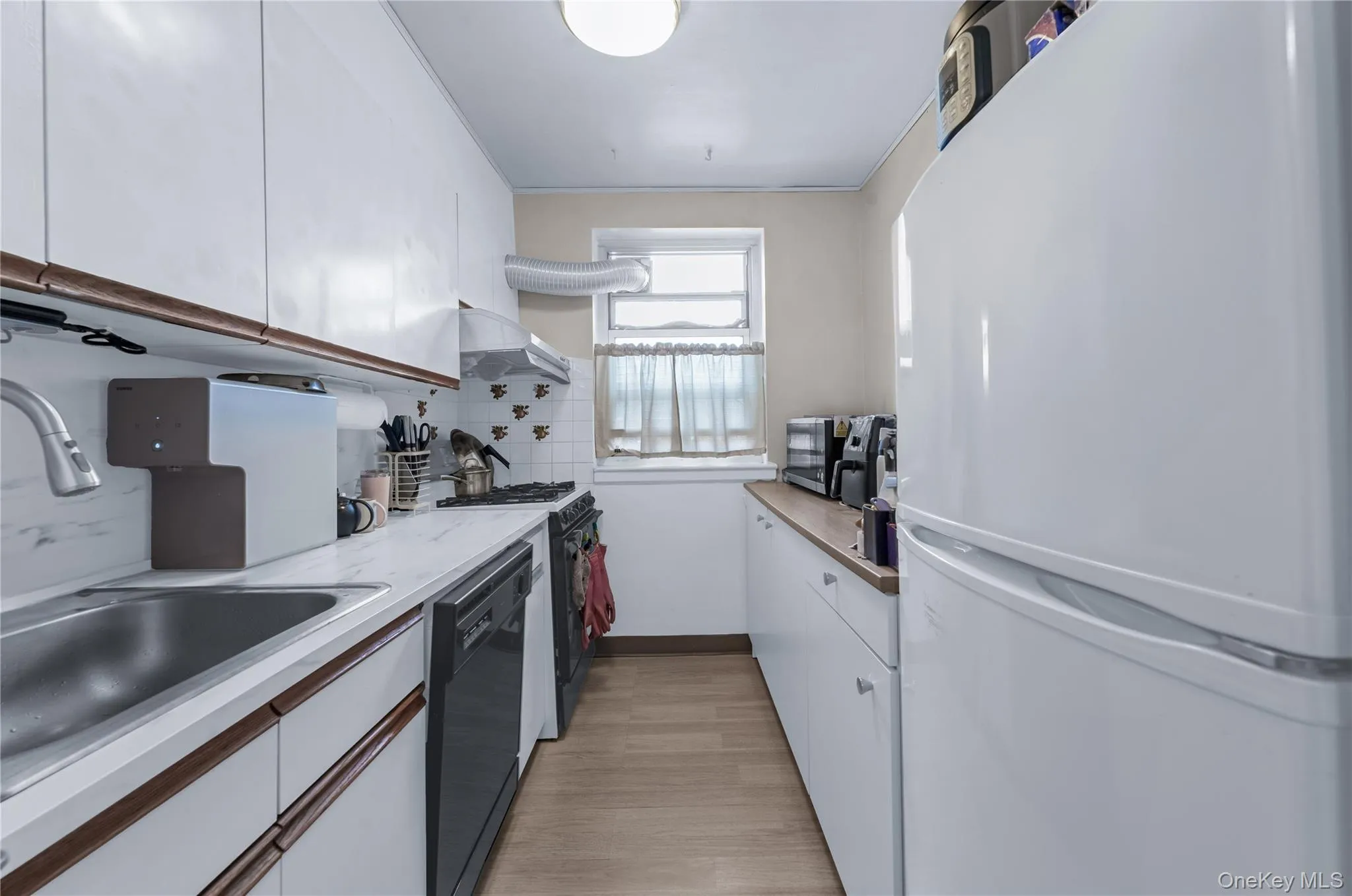 Kitchen featuring white cabinetry, black appliances, light countertops, and backsplash Kitchen featuring white cabinetry, black appliances, light countertops, and backsplash