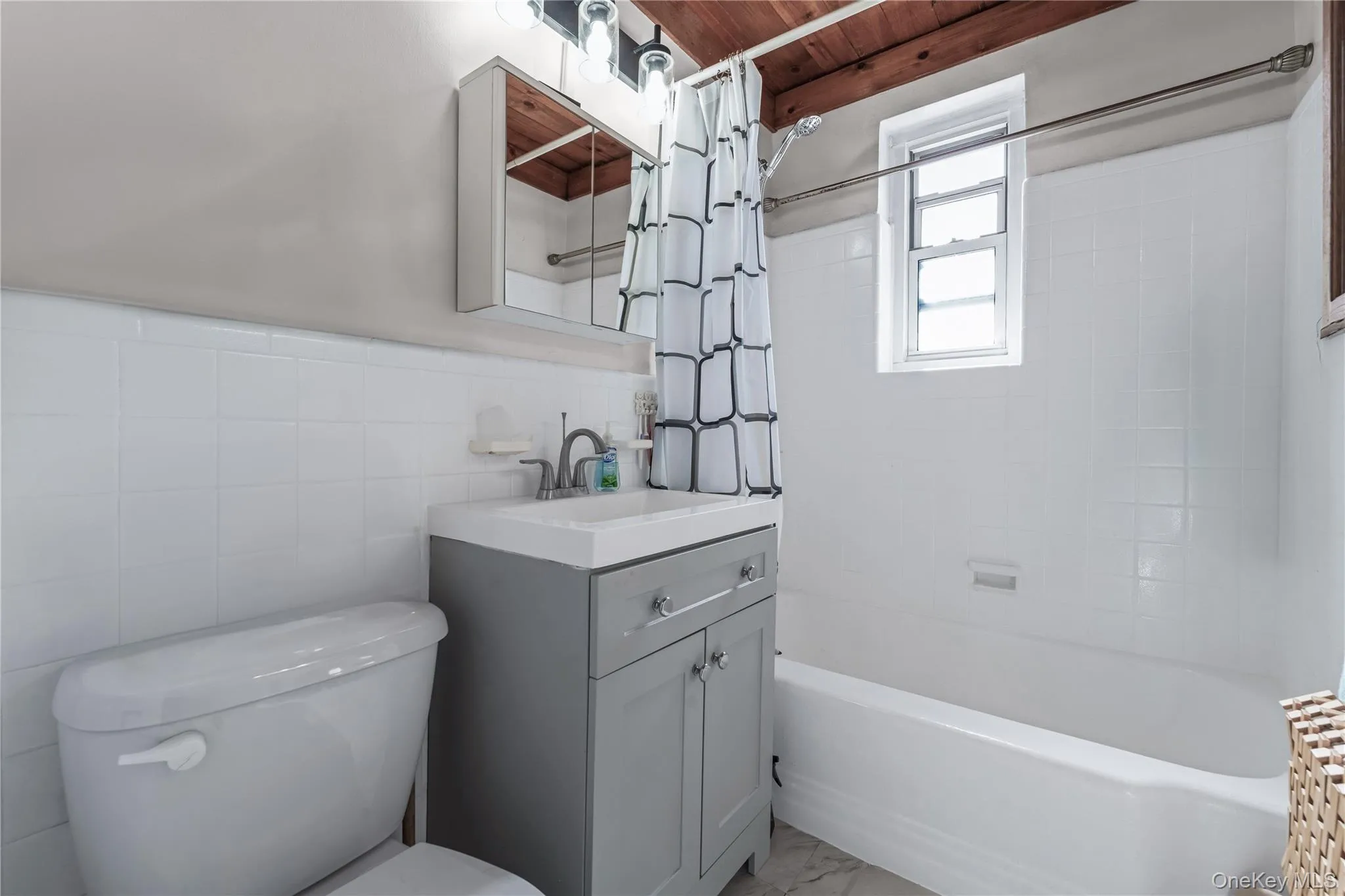 Bathroom featuring shower / bath combo with shower curtain, vanity, and tile walls Bathroom featuring shower / bath combo with shower curtain, vanity, and tile walls