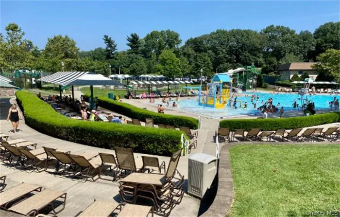 Community aquatic area featuring a large swimming pool, a separate shallow play pool with water features, and surrounding concrete lounge decks Community aquatic area featuring a large swimming pool, a separate shallow play pool with water features, and surrounding concrete lounge decks