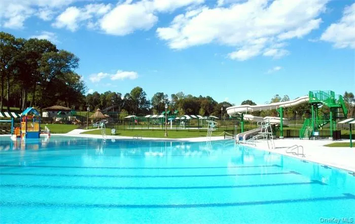 Expansive aquatic facility featuring a large swimming pool, an additional children's water play structure, and multiple water slides Expansive aquatic facility featuring a large swimming pool, an additional children's water play structure, and multiple water slides