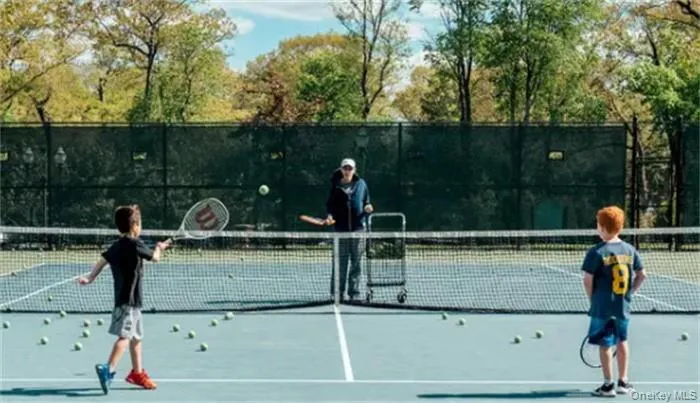 Full-size tennis court featuring a light blue playing surface, white demarcation lines, and a dark net Full-size tennis court featuring a light blue playing surface, white demarcation lines, and a dark net