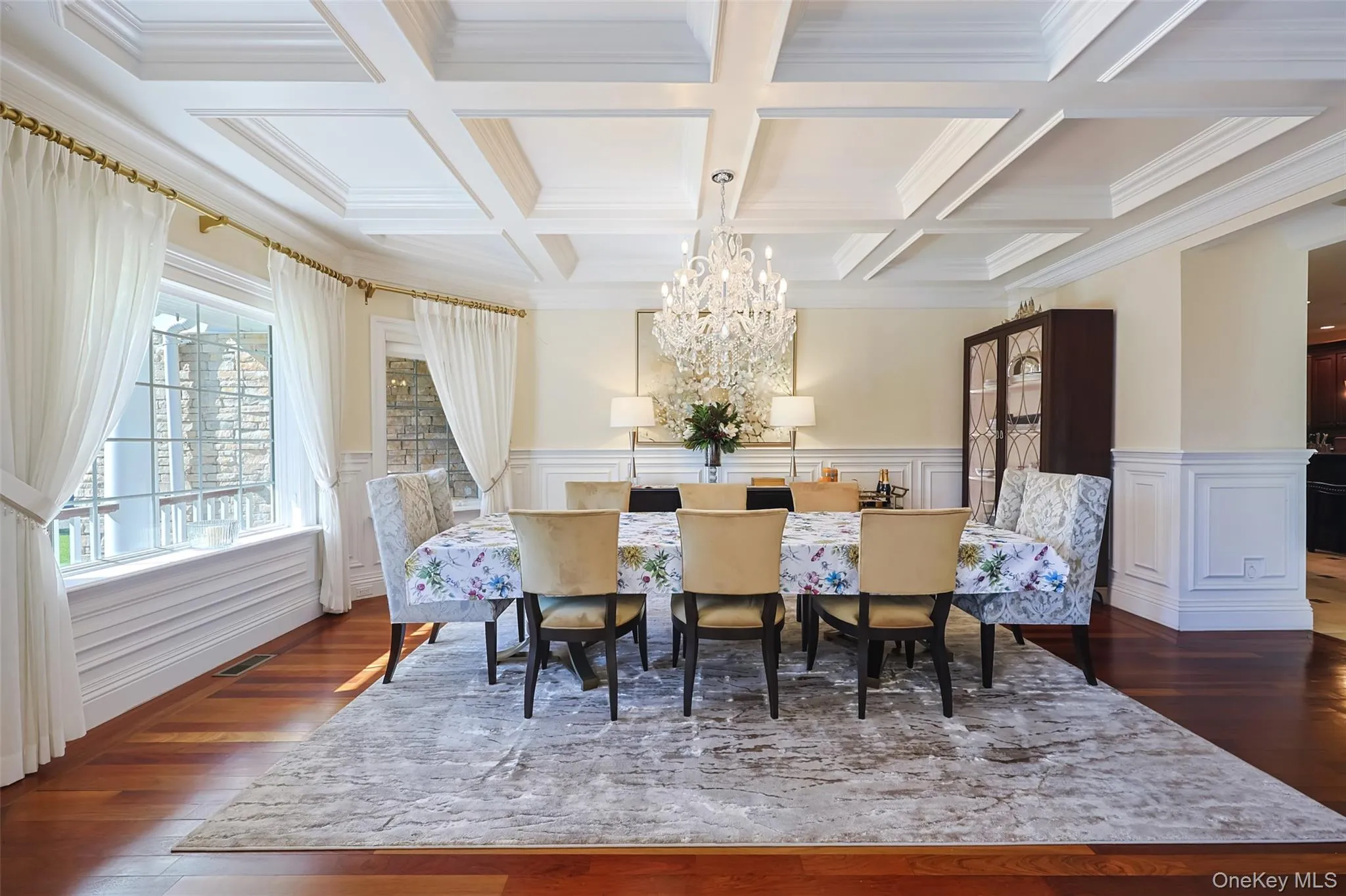 Formal dining space featuring coffered ceilings, hardwood flooring, and wainscoting Formal dining space featuring coffered ceilings, hardwood flooring, and wainscoting