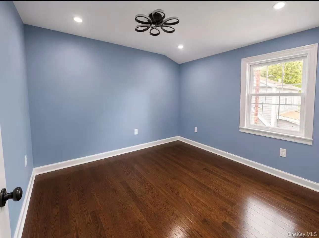 Room with wood-finish flooring, light blue walls, and white trim Room with wood-finish flooring, light blue walls, and white trim