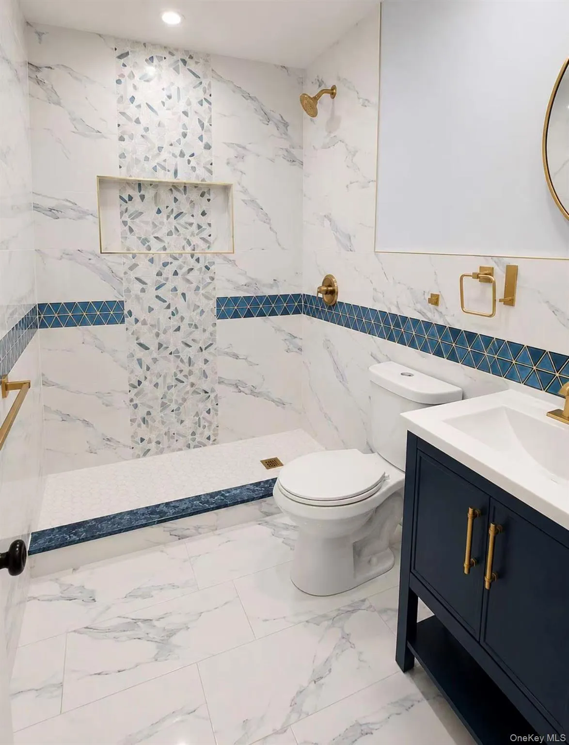 White marble-look tile flooring and wall surround with a blue geometric accent band White marble-look tile flooring and wall surround with a blue geometric accent band