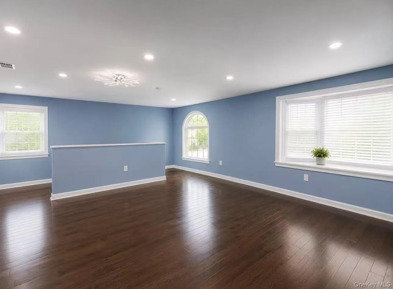 Living room featuring wood-finish flooring, recessed lighting, and multiple windows with white blinds Living room featuring wood-finish flooring, recessed lighting, and multiple windows with white blinds