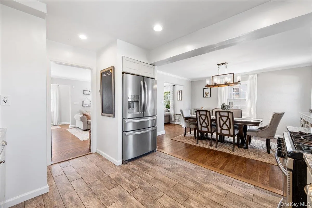 Kitchen area featuring wood-finish tile flooring, a stainless steel refrigerator, and recessed lighting and open to the dining room Kitchen area featuring wood-finish tile flooring, a stainless steel refrigerator, and recessed lighting and open to the dining room