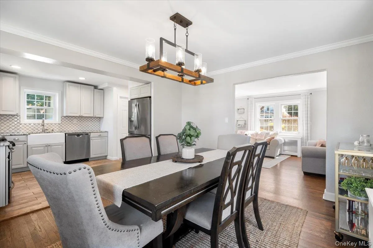 Dining area featuring hardwood flooring, a contemporary linear chandelier, and an open concept layout Dining area featuring hardwood flooring, a contemporary linear chandelier, and an open concept layout
