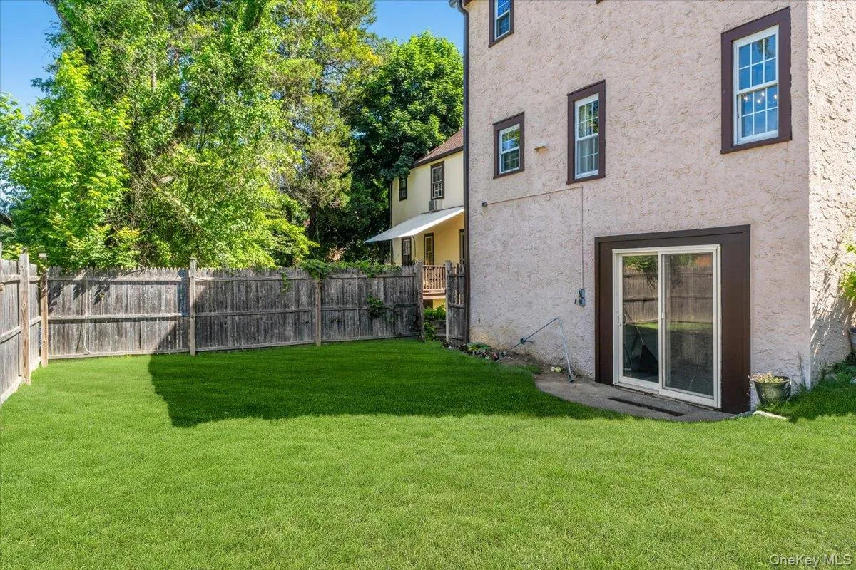 Expansive green lawn enclosed by a wooden privacy fence, featuring a direct-access sliding glass door to the property Expansive green lawn enclosed by a wooden privacy fence, featuring a direct-access sliding glass door to the property