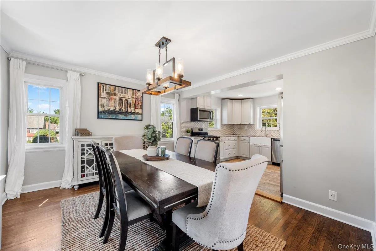 Dining area with wood-finish flooring, crown molding, and a modern rectangular chandelier Dining area with wood-finish flooring, crown molding, and a modern rectangular chandelier