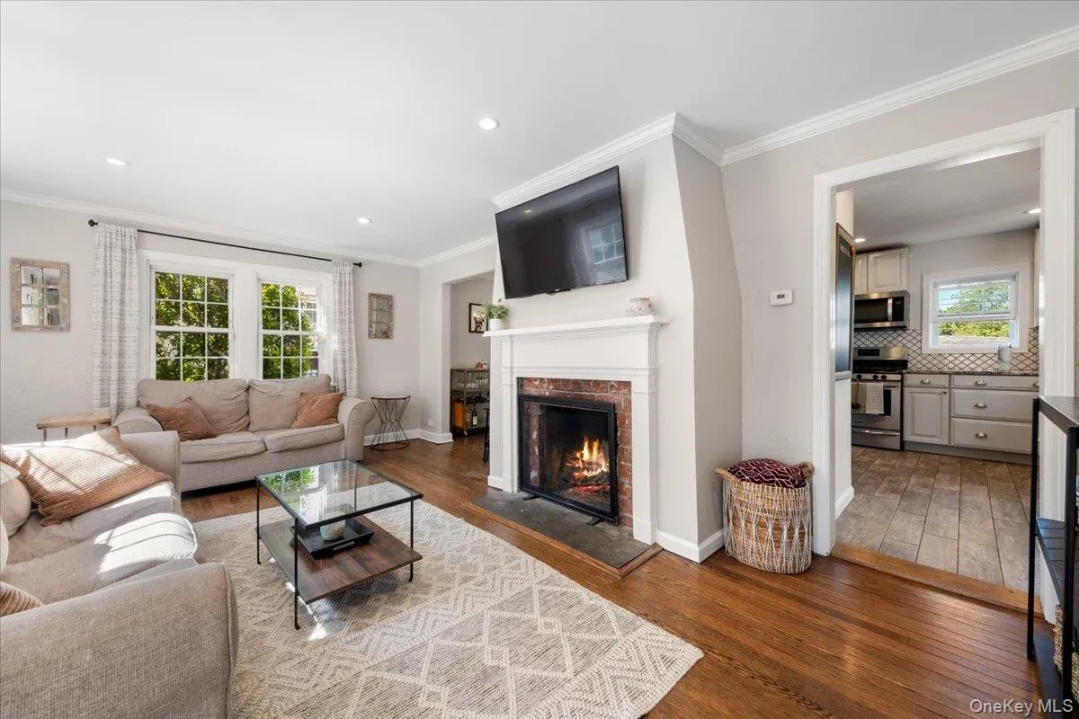 Living room with rich wood-finish flooring, recessed lighting, and crown molding Living room with rich wood-finish flooring, recessed lighting, and crown molding