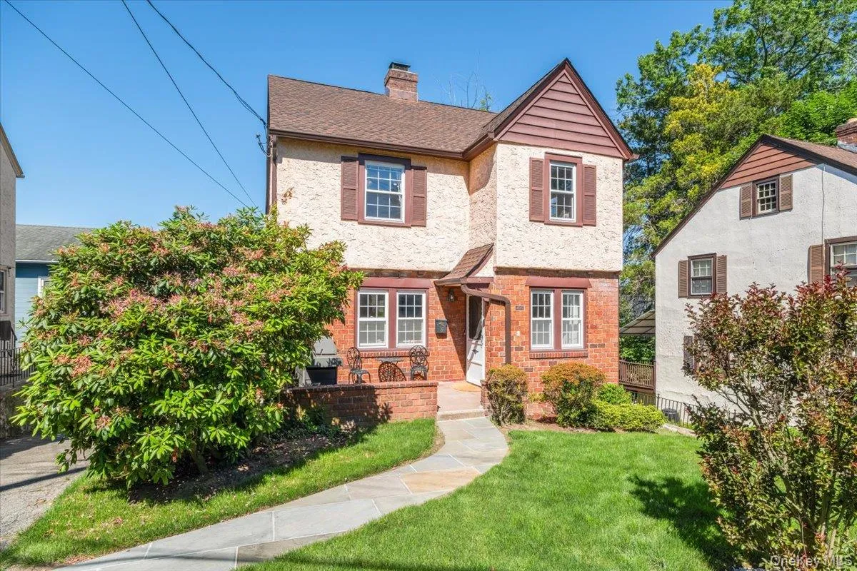 Two-story residence featuring a brick and stucco facade, brown shutters, and a prominent front gable Two-story residence featuring a brick and stucco facade, brown shutters, and a prominent front gable