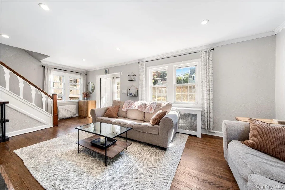 Spacious living area featuring wood-finish flooring, recessed lighting, and bright windows with white trim Spacious living area featuring wood-finish flooring, recessed lighting, and bright windows with white trim