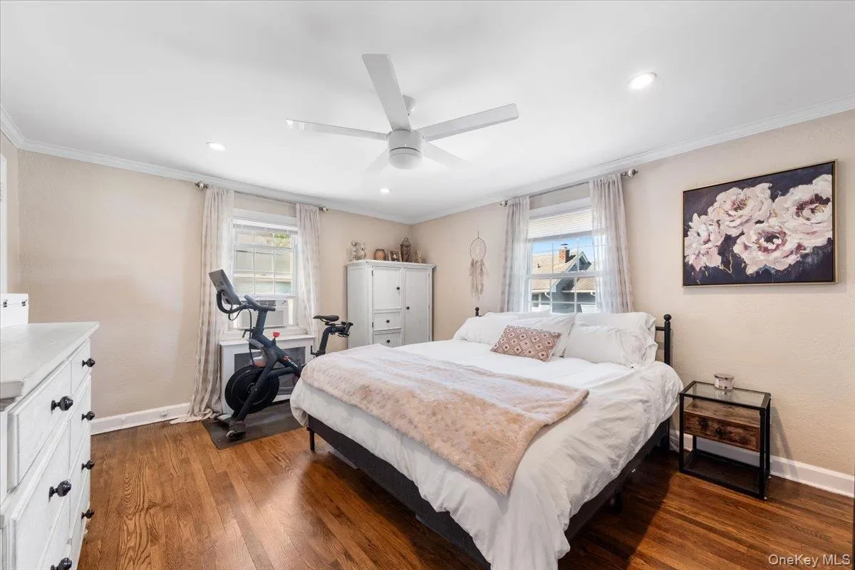 Bedroom with wood-finish flooring, white crown molding, recessed lighting, and a contemporary ceiling fan Bedroom with wood-finish flooring, white crown molding, recessed lighting, and a contemporary ceiling fan
