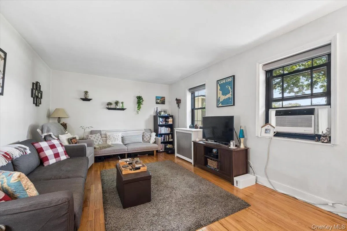 Bright living room featuring wood-finish flooring and multiple windows Bright living room featuring wood-finish flooring and multiple windows