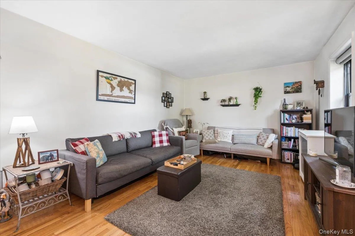 Bright living room featuring wood flooring, and a large window providing natural light Bright living room featuring wood flooring, and a large window providing natural light