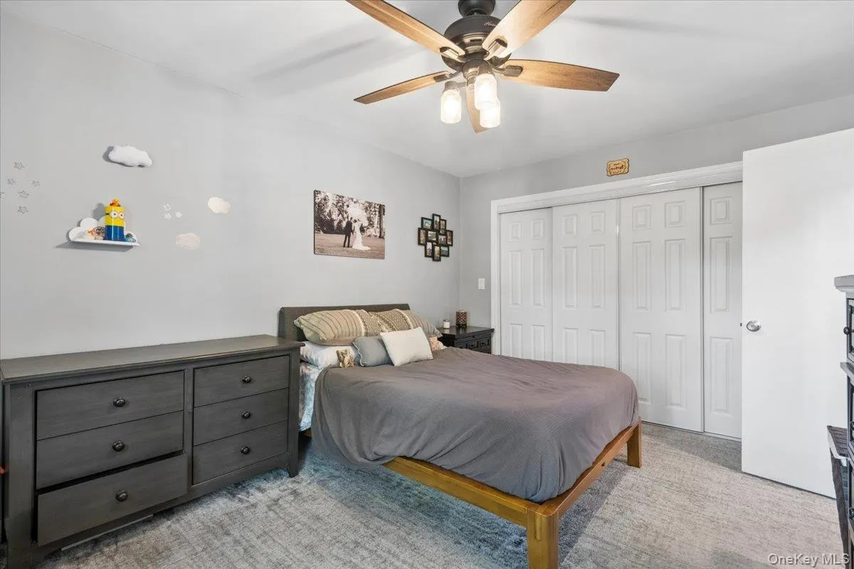 Bright room featuring light gray walls, a ceiling fan with integrated lighting, and large full wall closet Bright room featuring light gray walls, a ceiling fan with integrated lighting, and large full wall closet