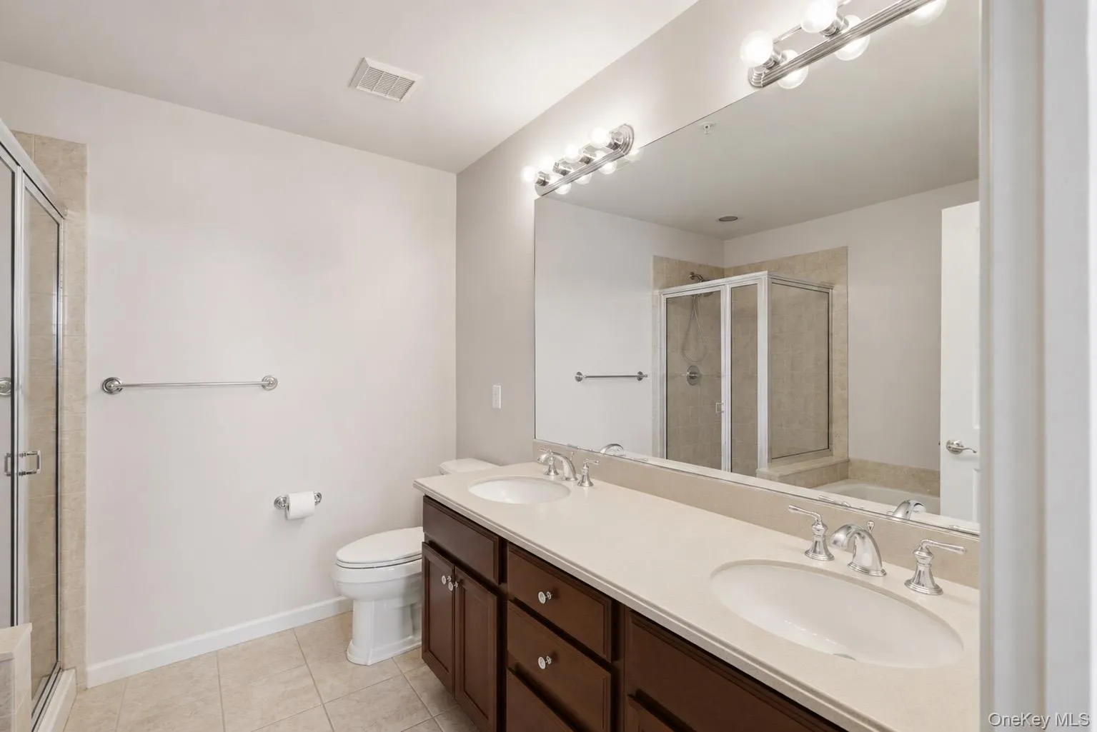 Dual vanity with undermount sinks and chrome fixtures, set against a large mirror with contemporary lighting Dual vanity with undermount sinks and chrome fixtures, set against a large mirror with contemporary lighting