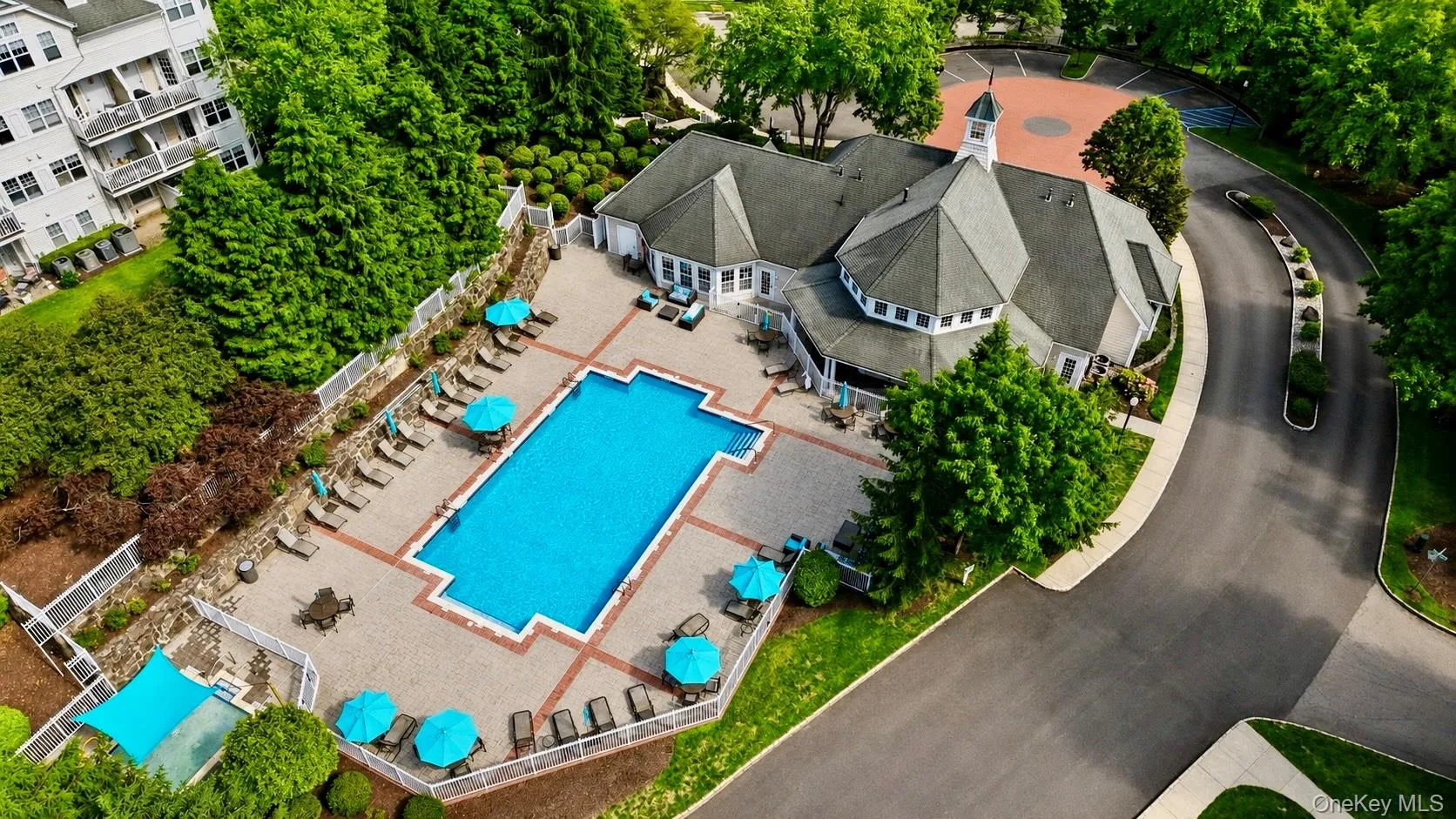Expansive outdoor swimming pool and kiddie pool with surrounding paver patio and lounge seating Expansive outdoor swimming pool and kiddie pool with surrounding paver patio and lounge seating