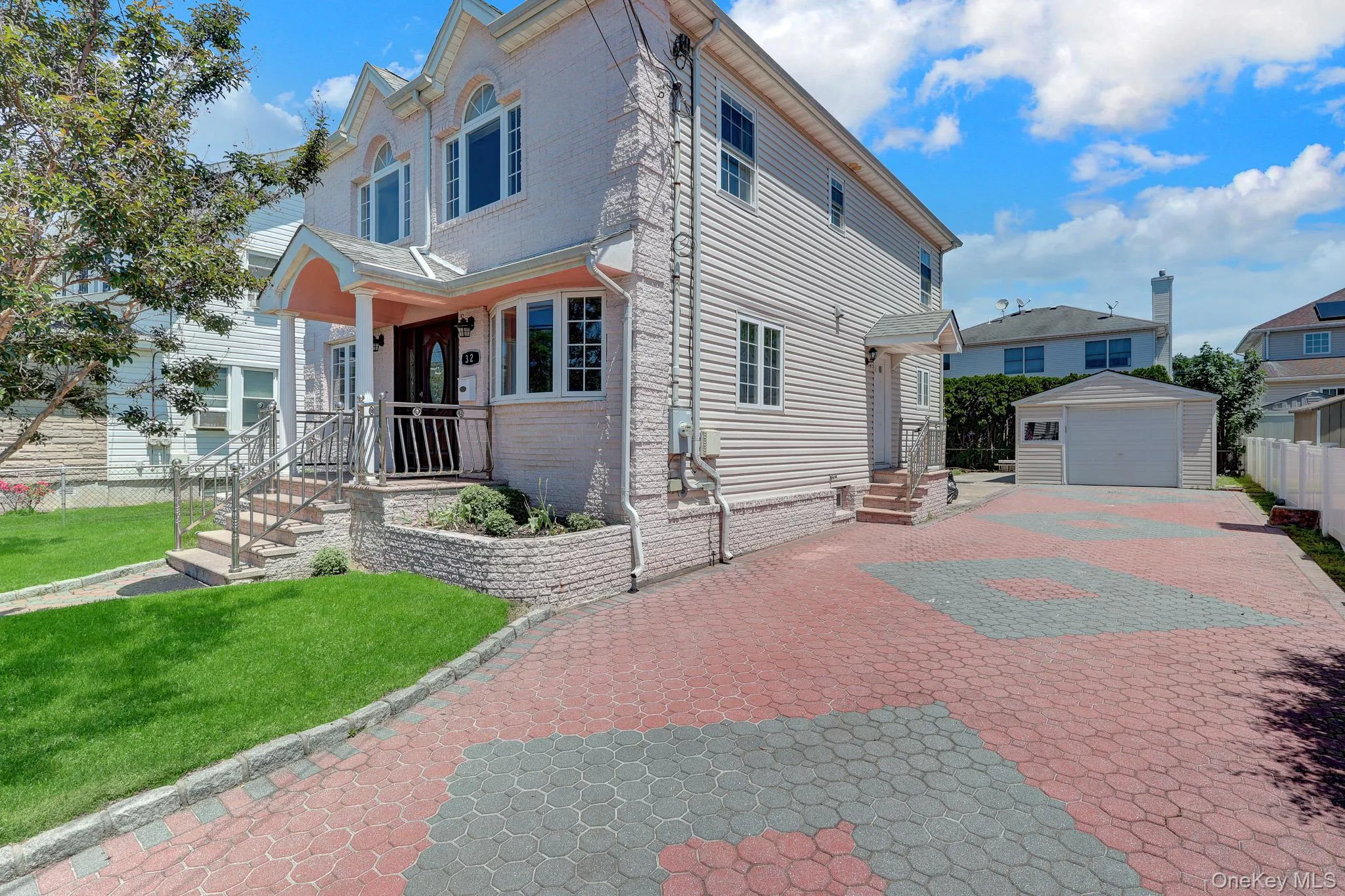Covered front porch, a patterned paver driveway, an attached garage, and a detached single-car garage Covered front porch, a patterned paver driveway, an attached garage, and a detached single-car garage