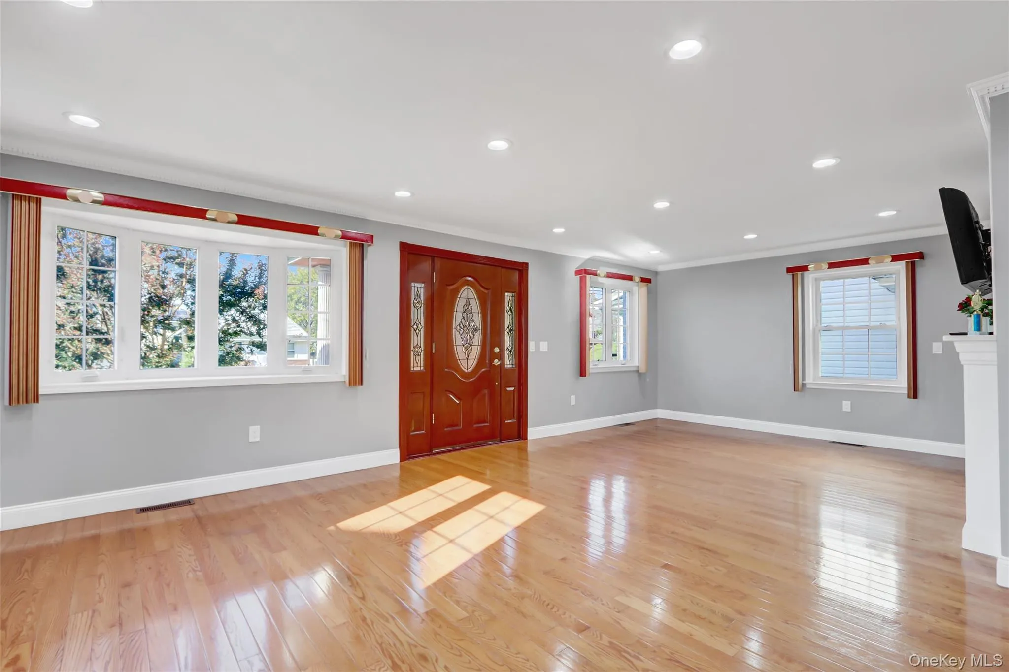Entryway featuring a wood-finish door with decorative glass inserts, hardwood flooring, bay window, recessed lighting and crown molding Entryway featuring a wood-finish door with decorative glass inserts, hardwood flooring, bay window, recessed lighting and crown molding