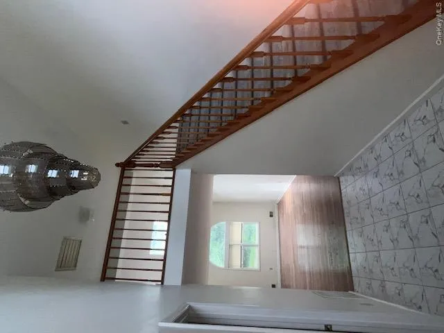 Two-story foyer featuring a tiered chandelier, tile flooring, and a staircase with wood banisters Two-story foyer featuring a tiered chandelier, tile flooring, and a staircase with wood banisters