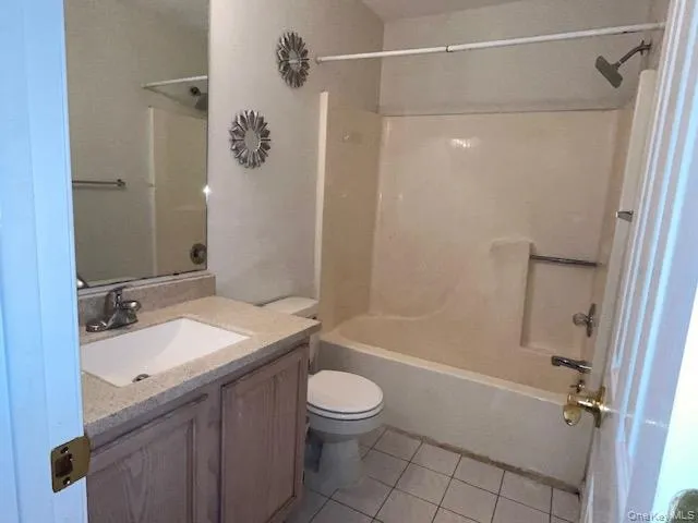 Full Bathroom with a combination tub and shower unit, a vanity featuring a beige countertop and an undermount sink, and a large wall-mounted mirror Full Bathroom with a combination tub and shower unit, a vanity featuring a beige countertop and an undermount sink, and a large wall-mounted mirror