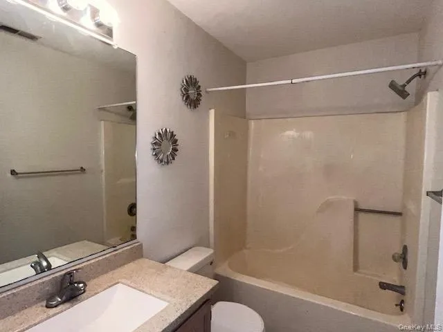 Full Bathroom with a combination tub and shower unit, a vanity featuring a beige countertop and an undermount sink, and a large wall-mounted mirror Full Bathroom with a combination tub and shower unit, a vanity featuring a beige countertop and an undermount sink, and a large wall-mounted mirror