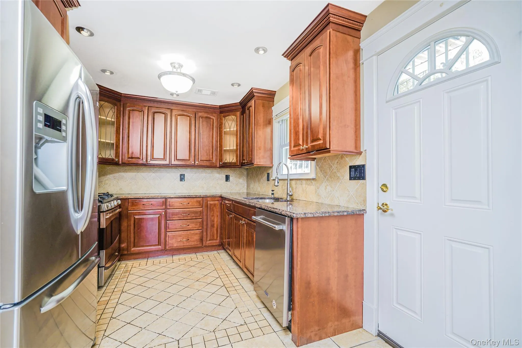 Kitchen featuring wood cabinetry with crown molding, stainless steel appliances, granite countertops, and a tiled backsplash Kitchen featuring wood cabinetry with crown molding, stainless steel appliances, granite countertops, and a tiled backsplash
