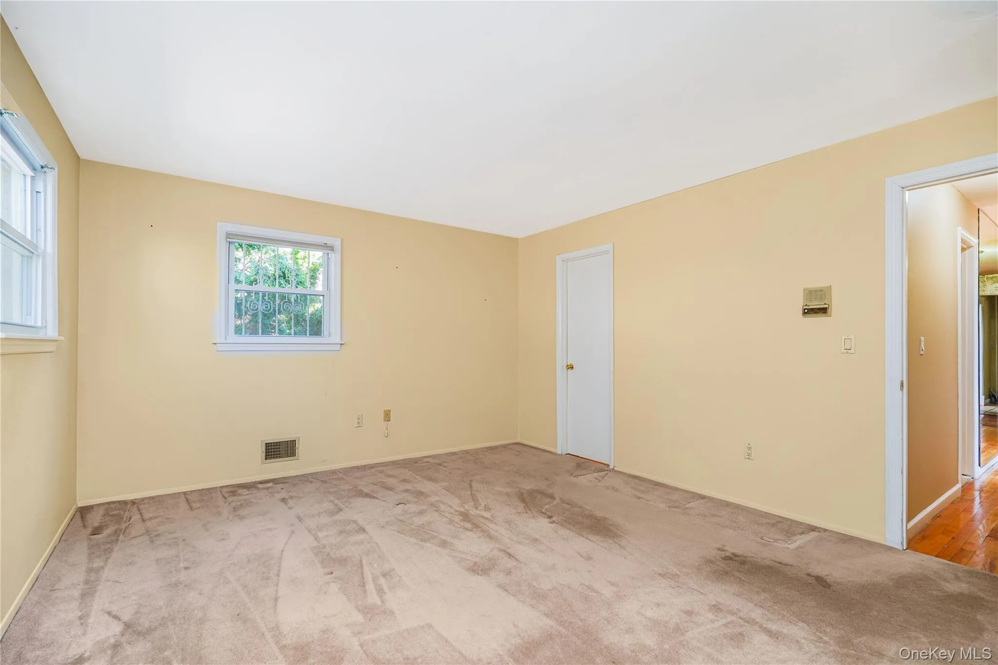Neutral-toned carpeted interior space with light-colored walls Neutral-toned carpeted interior space with light-colored walls