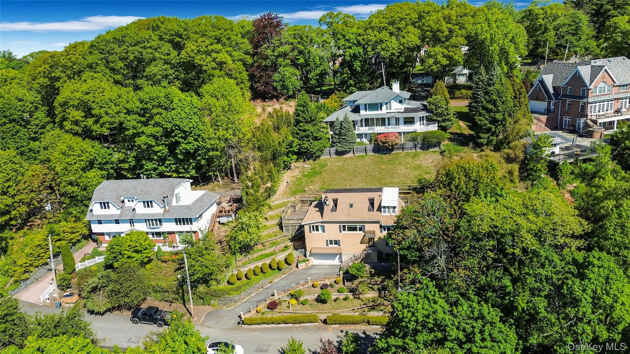 Split-level residence featuring a multi-gable roofline, attached garage, and a paved driveway Split-level residence featuring a multi-gable roofline, attached garage, and a paved driveway