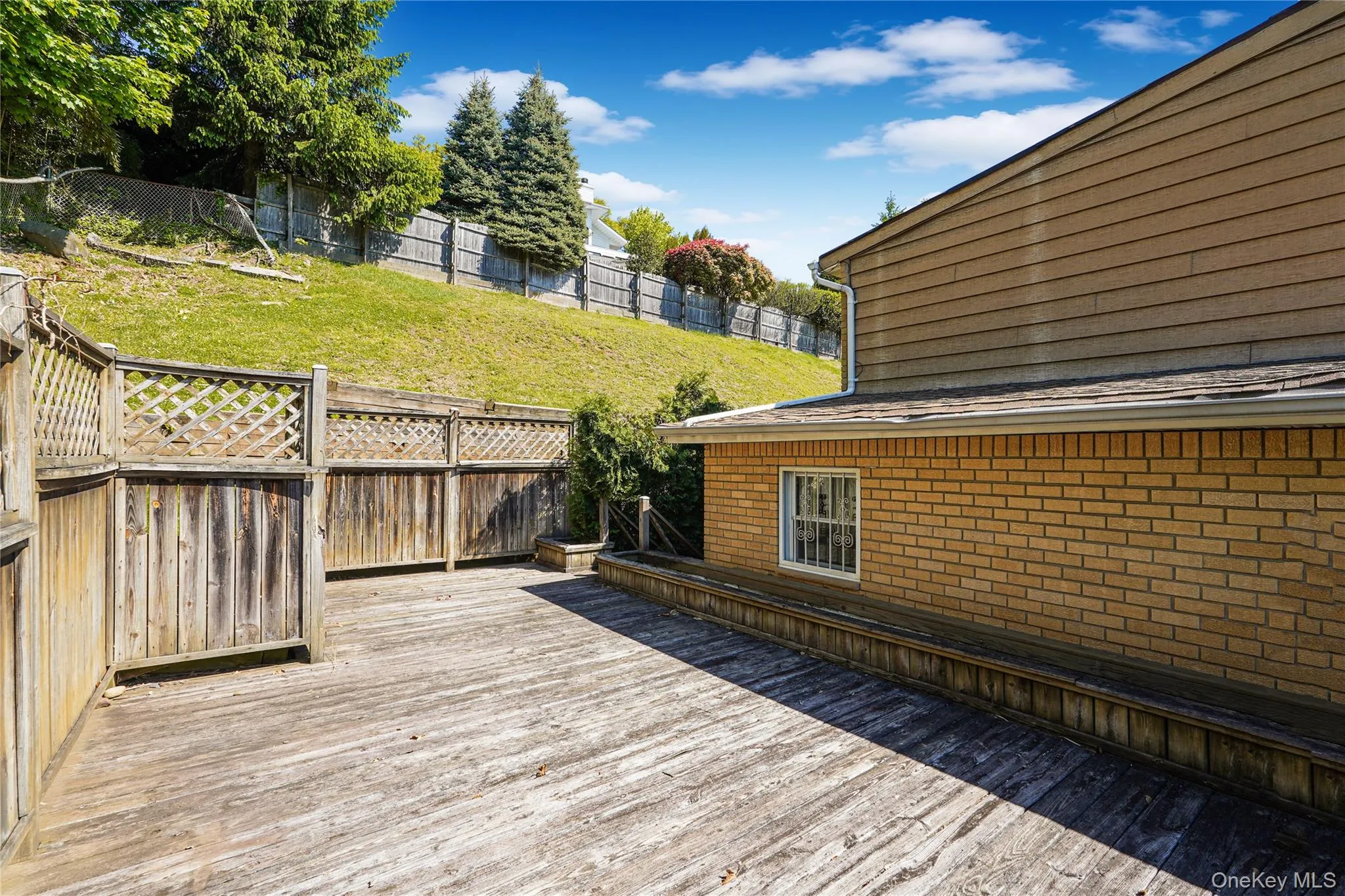 Spacious outdoor deck featuring natural wood decking and privacy lattice fencing Spacious outdoor deck featuring natural wood decking and privacy lattice fencing