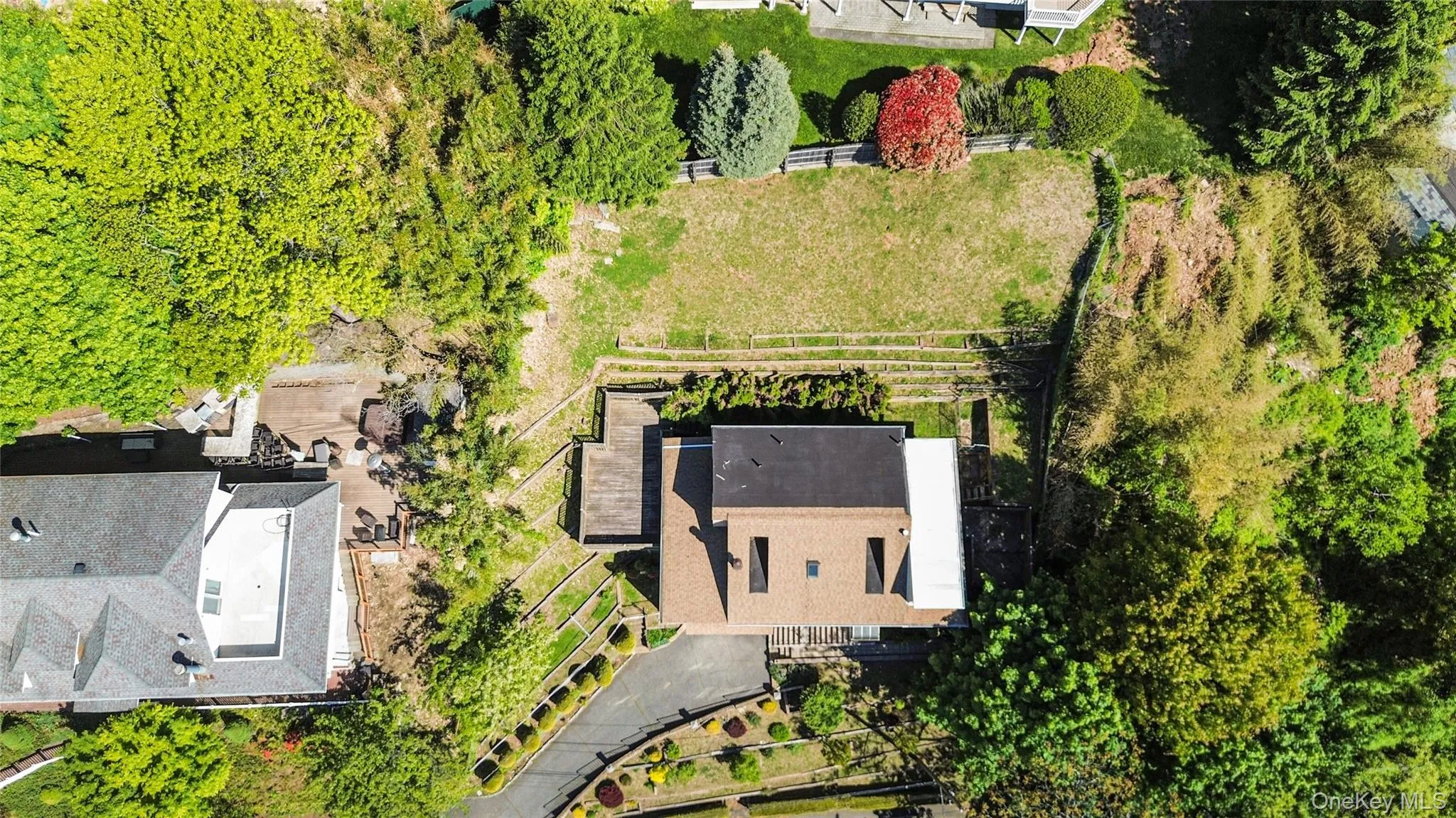 Terraced property featuring a flat roof structure with visible skylights, a pitched roof residence, and a multi-level wooden deck Terraced property featuring a flat roof structure with visible skylights, a pitched roof residence, and a multi-level wooden deck