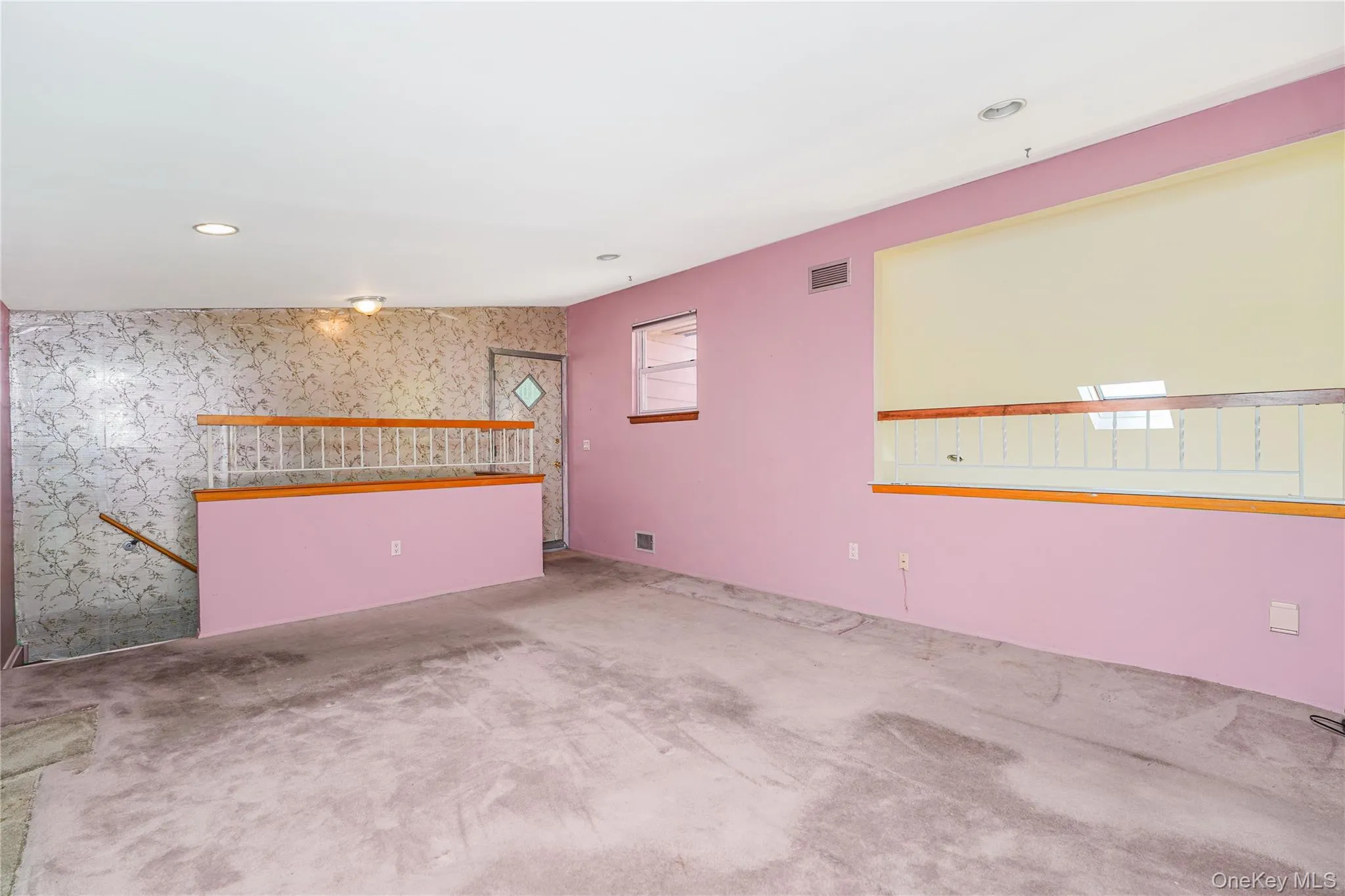 Carpeted room featuring a half-wall with a white spindle railing, recessed lighting, and a window with a roller shade Carpeted room featuring a half-wall with a white spindle railing, recessed lighting, and a window with a roller shade