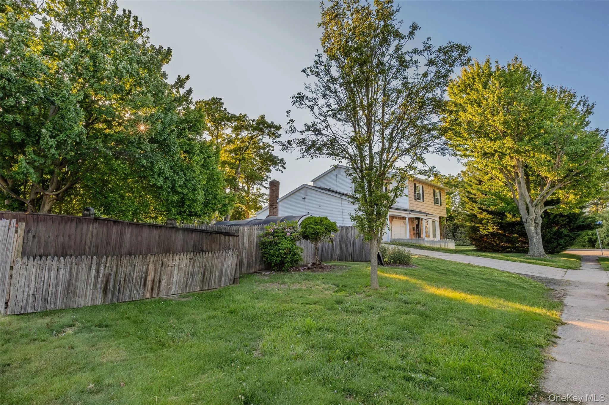Expansive lot featuring plenty of trees, a manicured lawn, and a wooden privacy fence Expansive lot featuring plenty of trees, a manicured lawn, and a wooden privacy fence