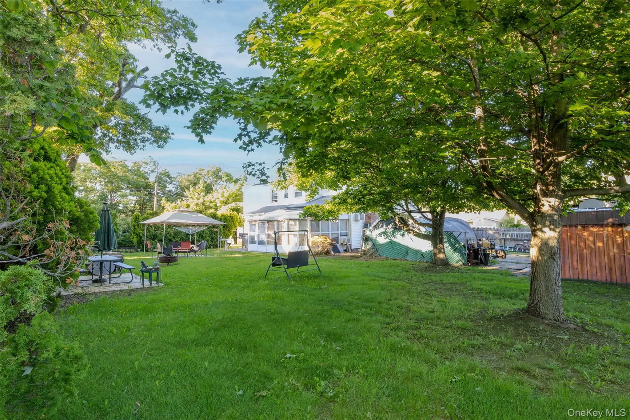 Expansive rear yard featuring mature shade trees and a patio area Expansive rear yard featuring mature shade trees and a patio area