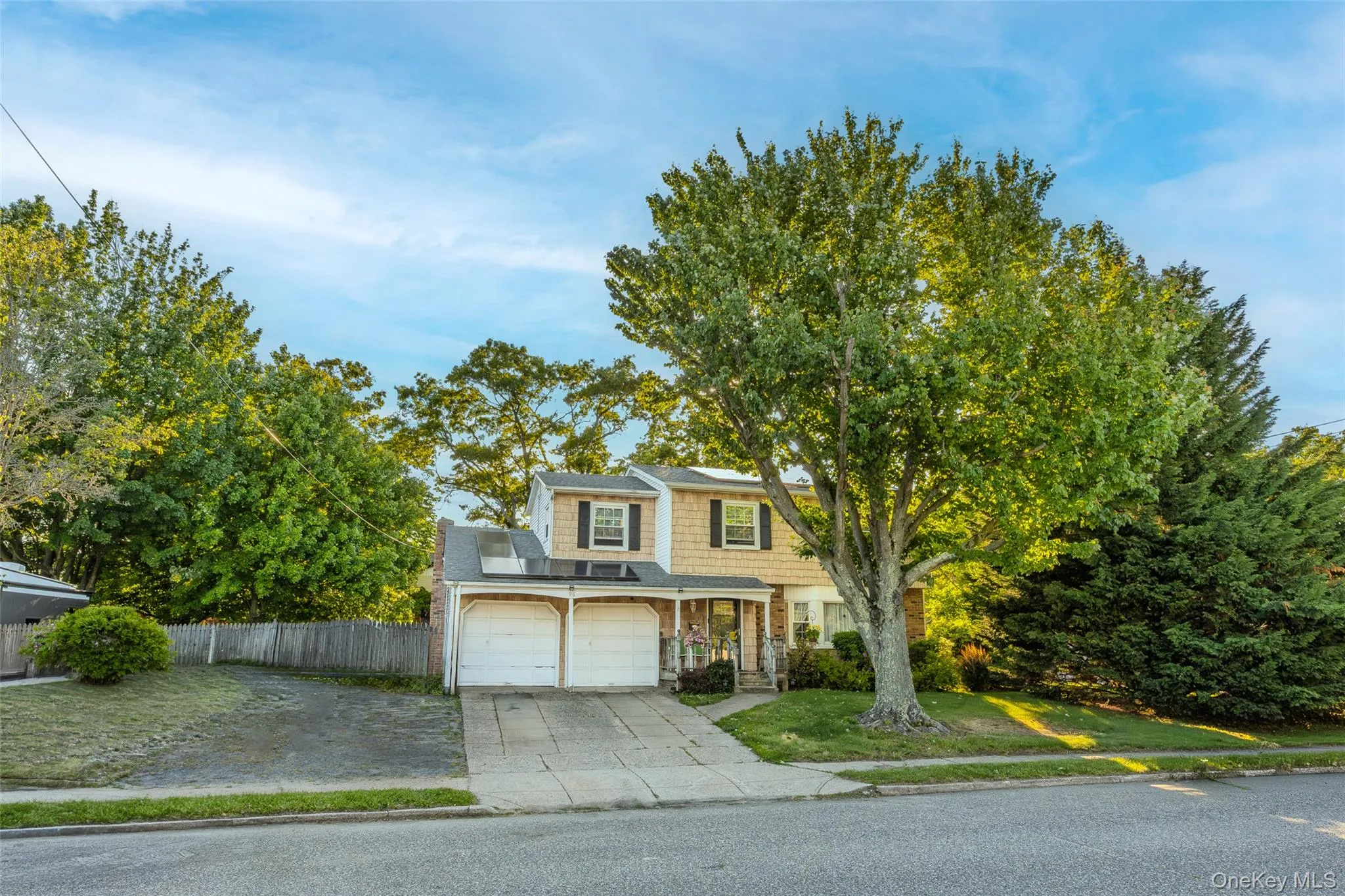 Colonial residence with a two-car garage with private driveway, mature front yard trees, and a wooden privacy fence Colonial residence with a two-car garage with private driveway, mature front yard trees, and a wooden privacy fence